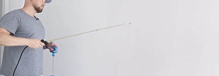 Person besprüht Wand mit Sprühflasche